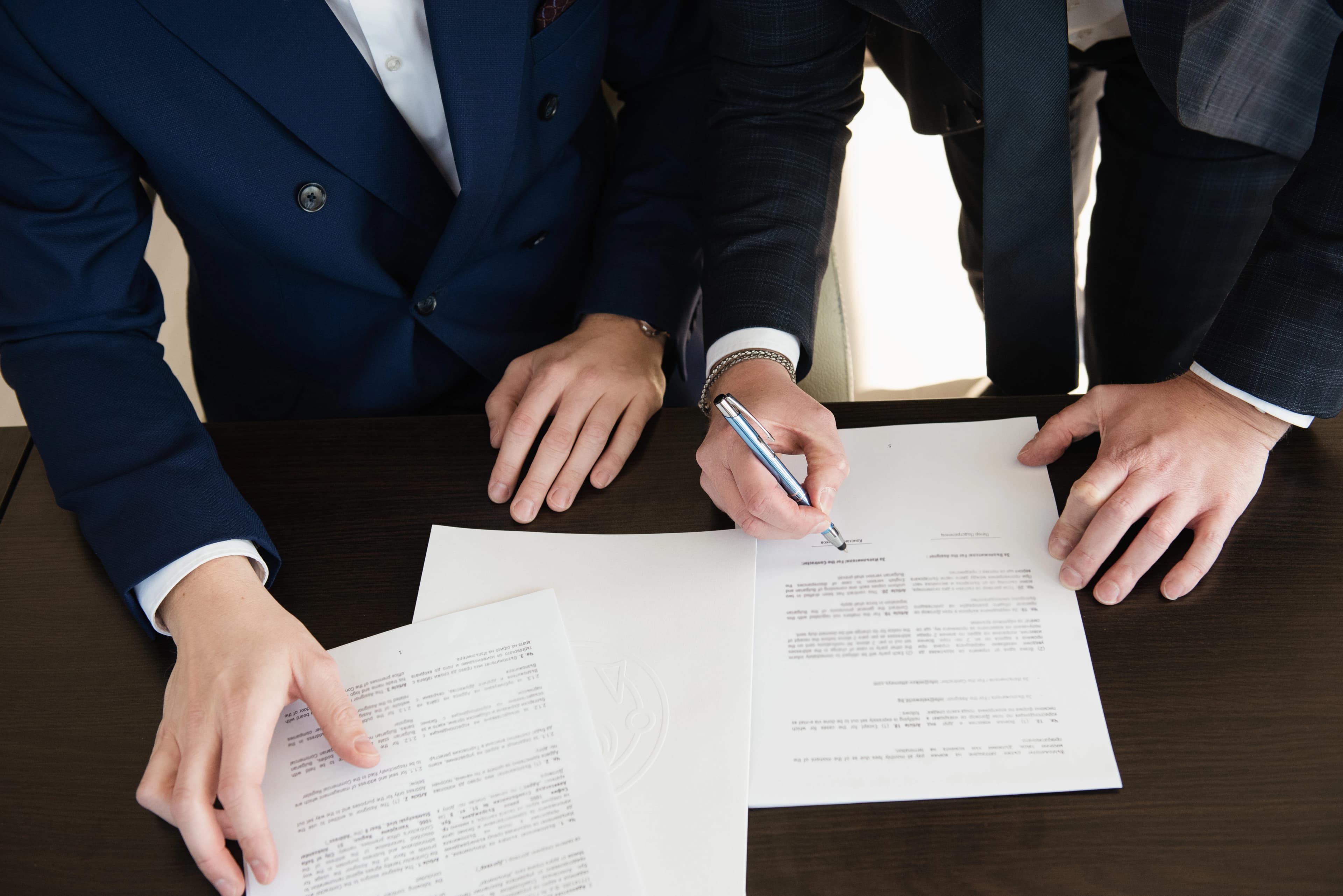 Hero image of two men in suits discussing some documents on a table